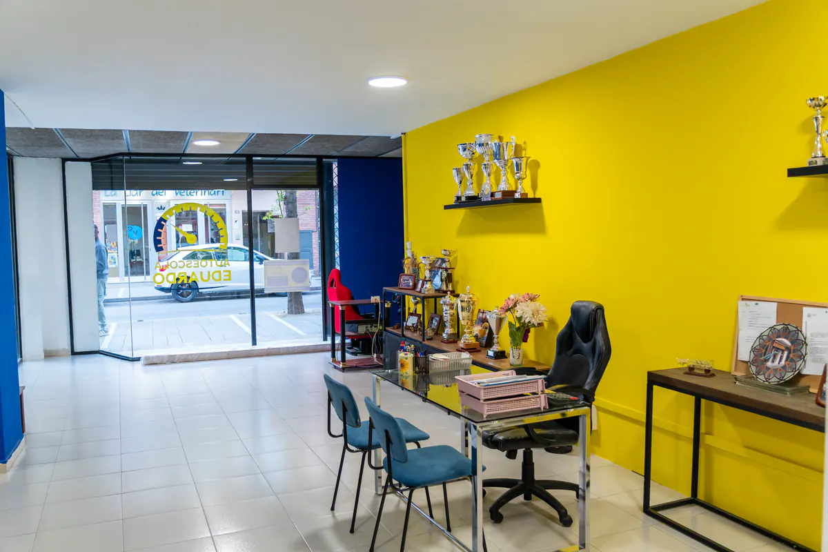 Recepción con la pared amarilla y los trofeos de la autoescuela