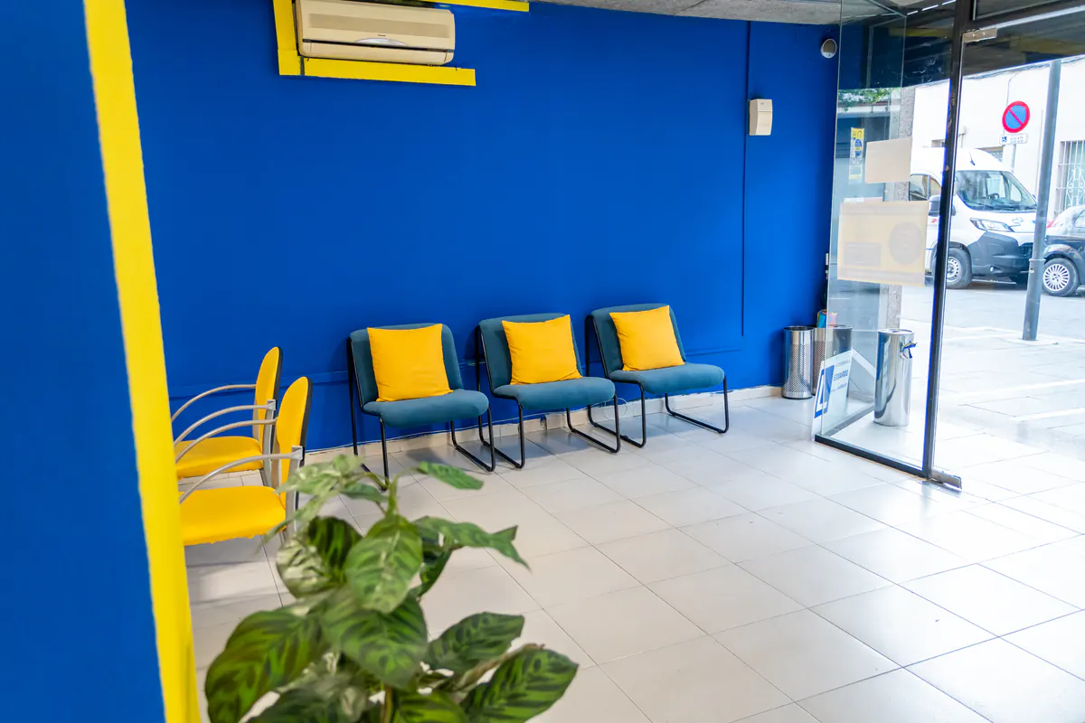 Sala de espera de la autoescuela con sillas amarillas y pared azul