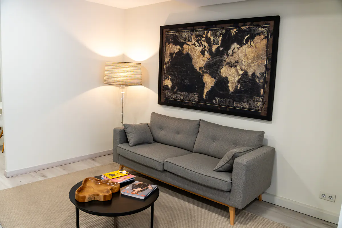 Sala de espera con sofá gris y mapa del mundo en la pared