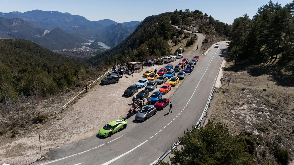 Coches del club aparcados en fila en un mirador de los Pirineos, vistos desde el aire