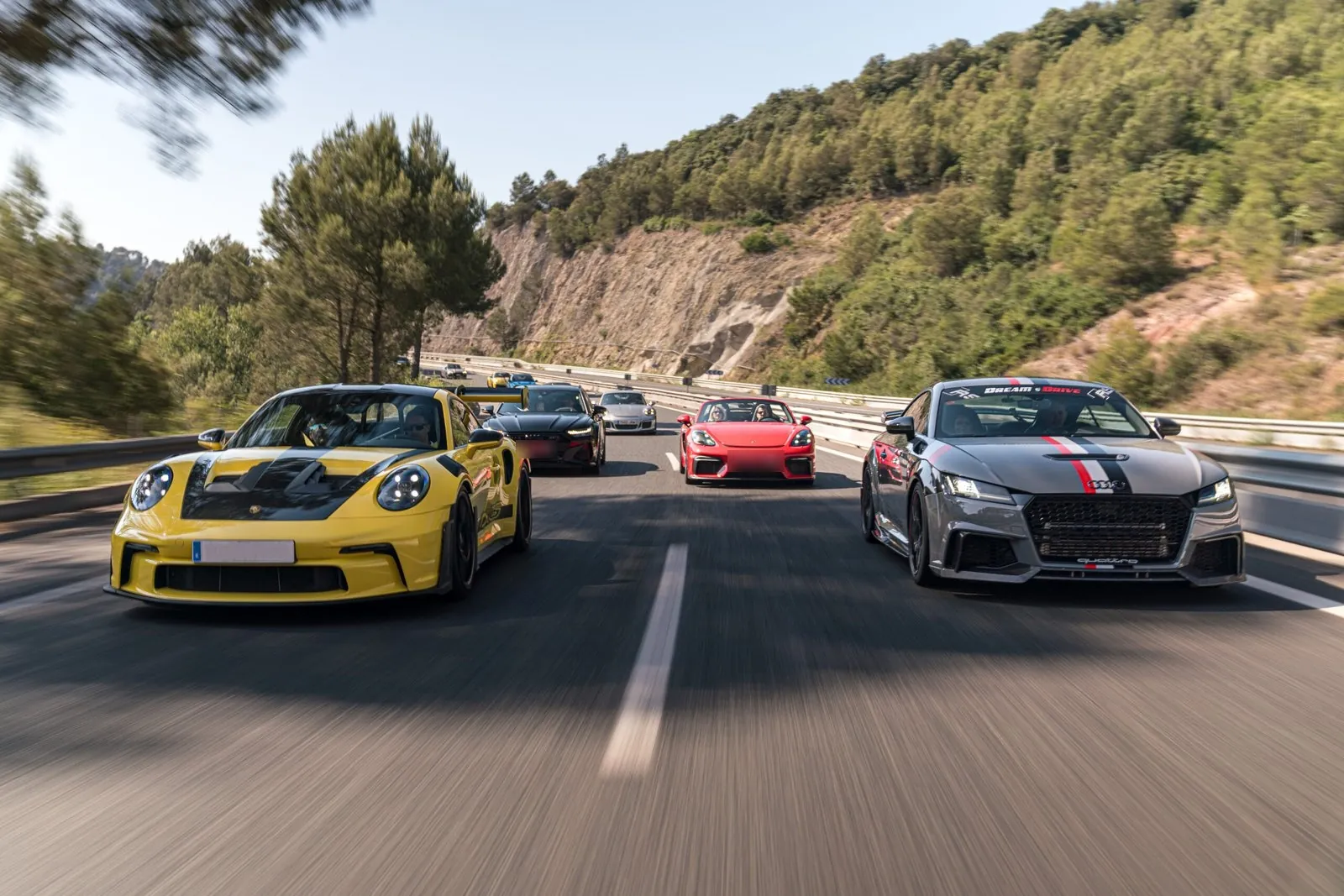 Porsche 911 GT3 amarillo al frente de la ruta de Dream & Drive por una carretera de montaña