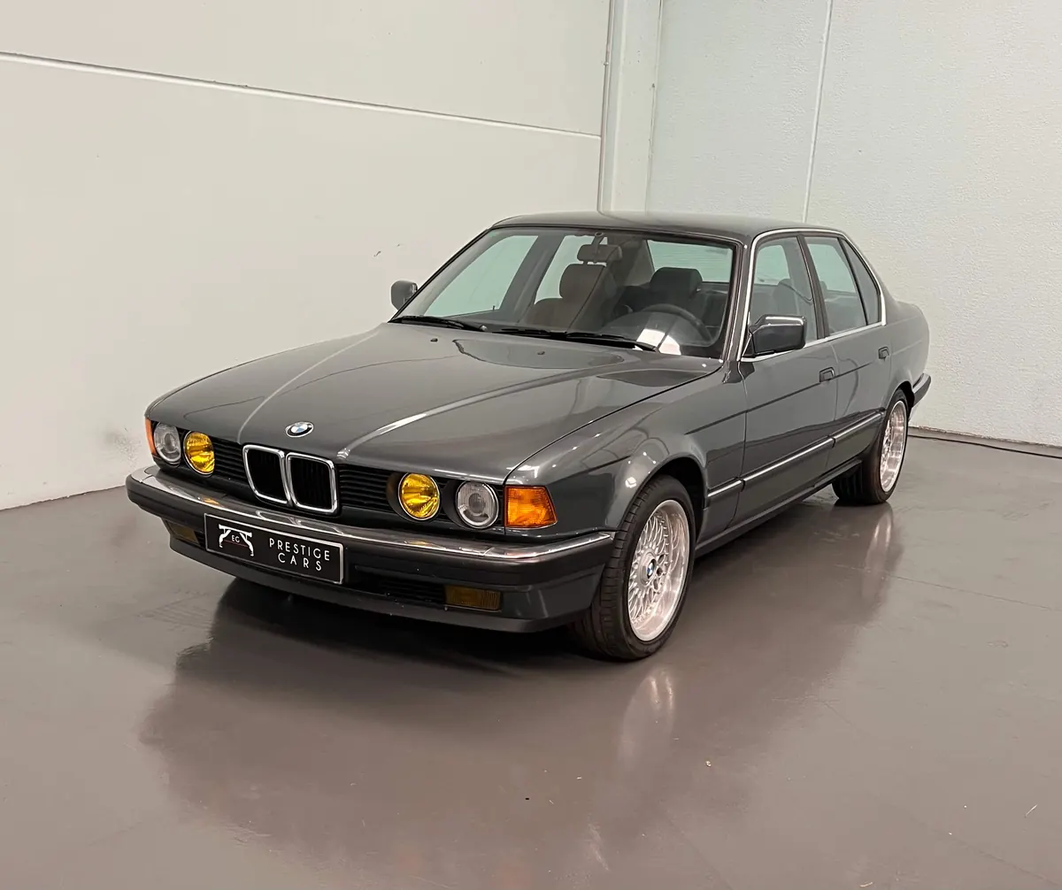 BMW Serie 7 E32 clásico con faros antiniebla amarillos en el showroom de EG