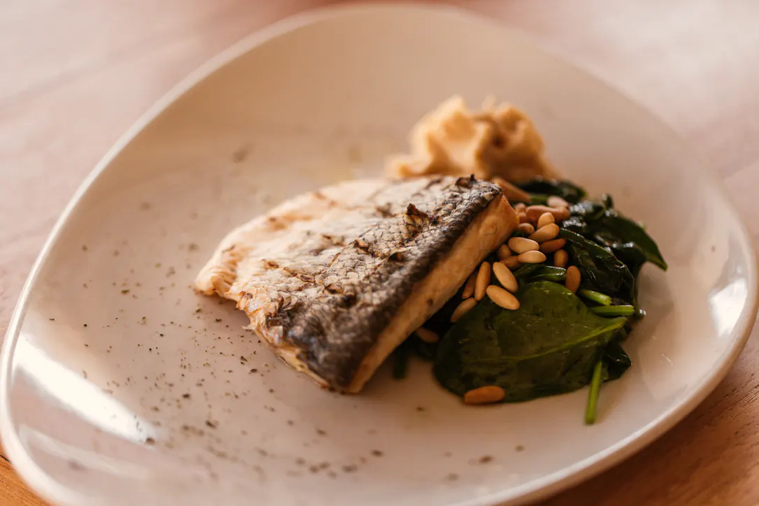 Plato de pescado con espinacas y piñones de la cocina de Elements