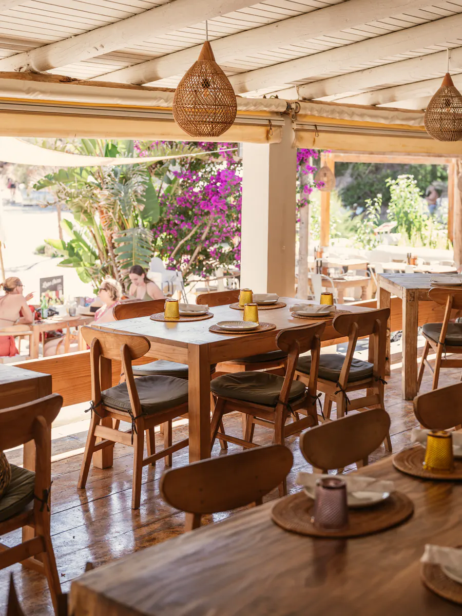 Terraza del restaurante de Elements Ibiza con mesas de madera, lámparas de mimbre y buganvilla