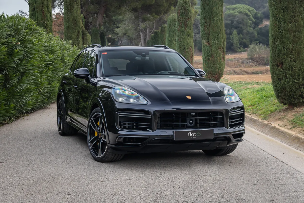 Porsche Cayenne Turbo S negro de frente en un camino de cipreses