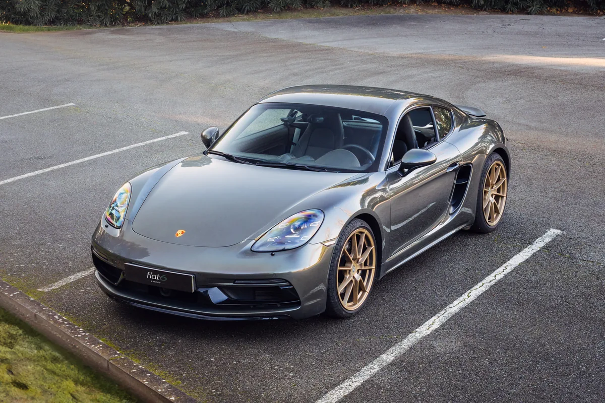 Porsche 718 Cayman GTS gris con llantas doradas y el portamatrículas de Flat6