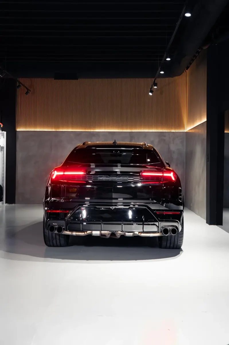 Trasera del Lamborghini Urus con los pilotos encendidos en el showroom