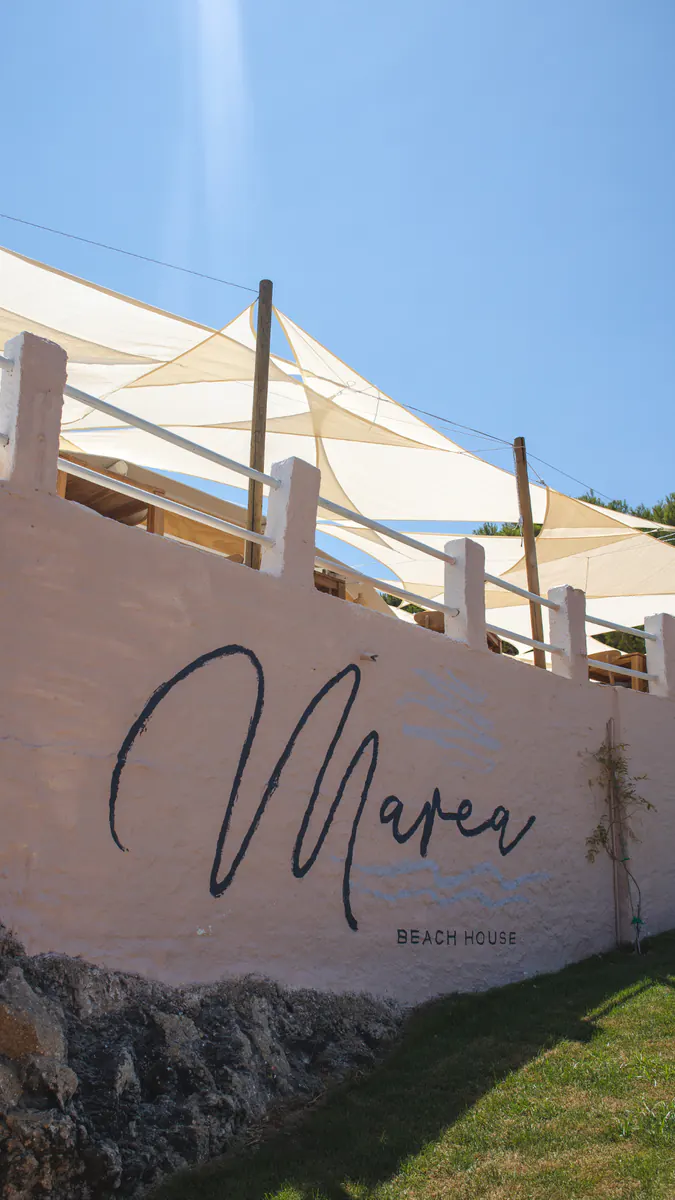 Logotipo de Marea Beach House pintado en el muro blanco de la entrada