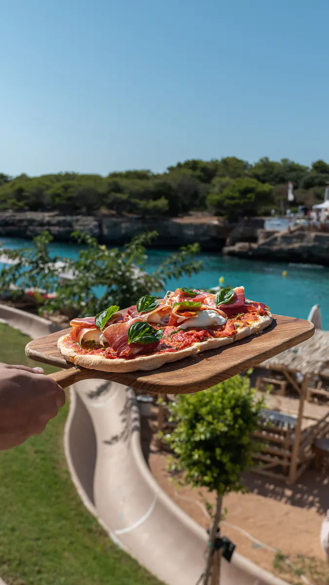 Pizza de Forno di Marea servida en tabla, con la cala de fondo