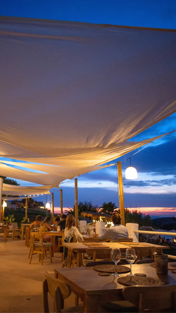 Terraza de Marea al anochecer bajo las velas, con las mesas iluminadas