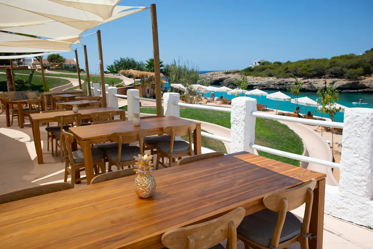 Terraza del restaurante de Marea con mesas de madera mirando a la cala