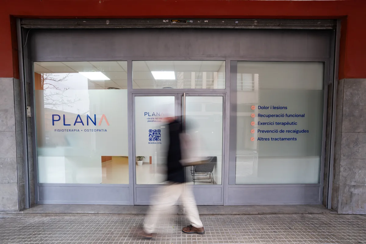 Fachada de Plana Fisio con los vinilos del escaparate y una persona pasando por delante