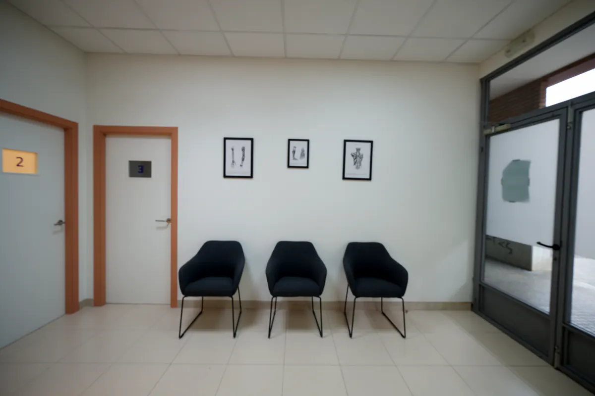 Sala de espera de Plana Fisio con butacas negras y cuadros de anatomía