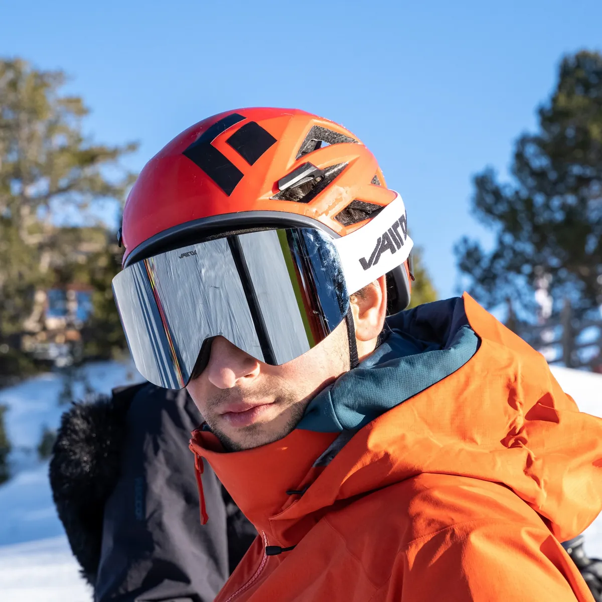 Esquiador con la máscara Vairok SW y casco naranja en la nieve